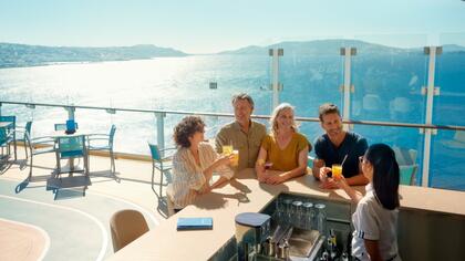 Vier Personen an einer Bar auf dem Deck eines Mein Schiff Kreuzfahrtschiffs